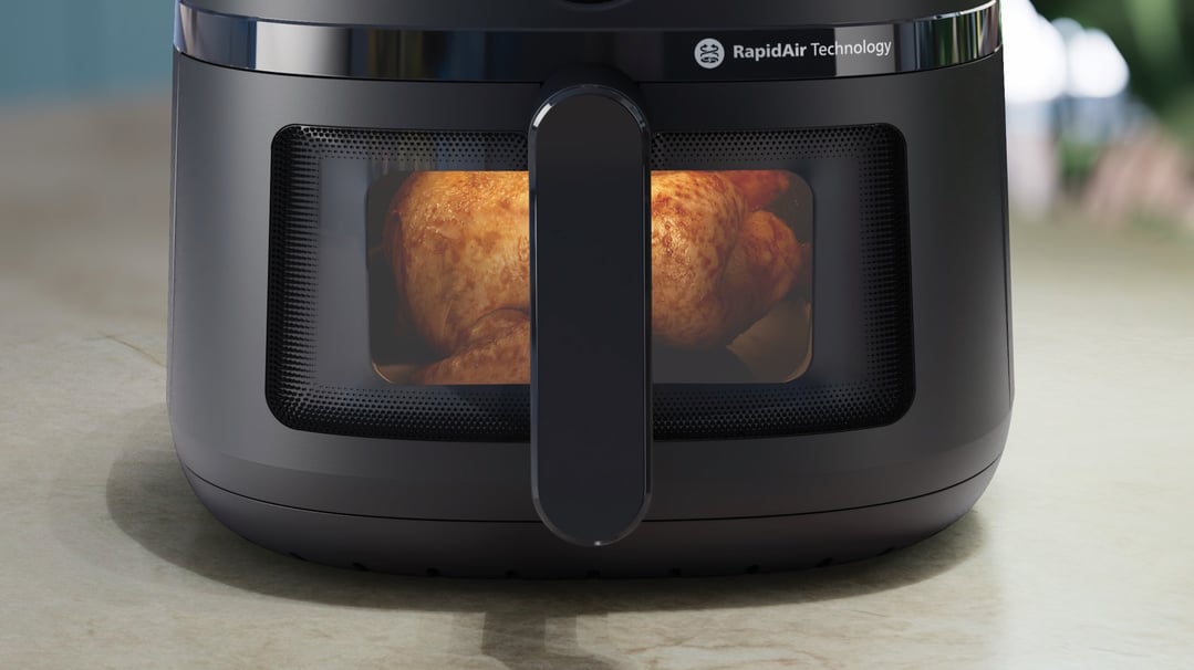 Black airfryer with a whole roasted chicken visible through the window