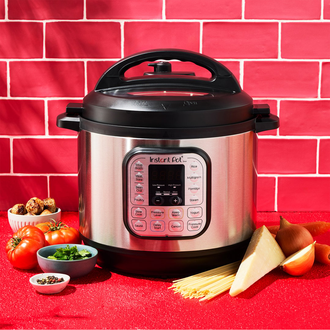 Instant multi-pressure slow cooker with ingredients on a red countertop