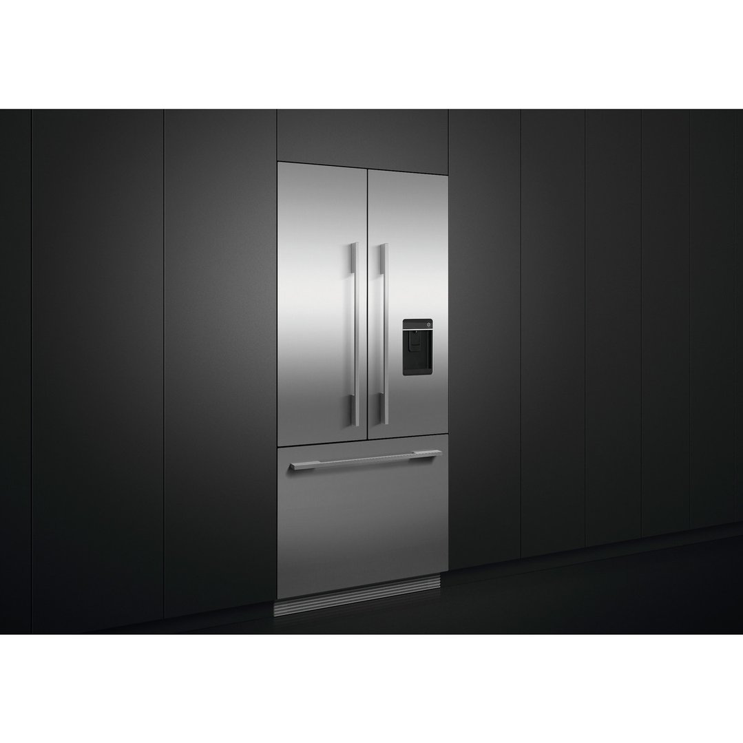 Stainless steel French door refrigerator freezer with ice and water in a dark kitchen