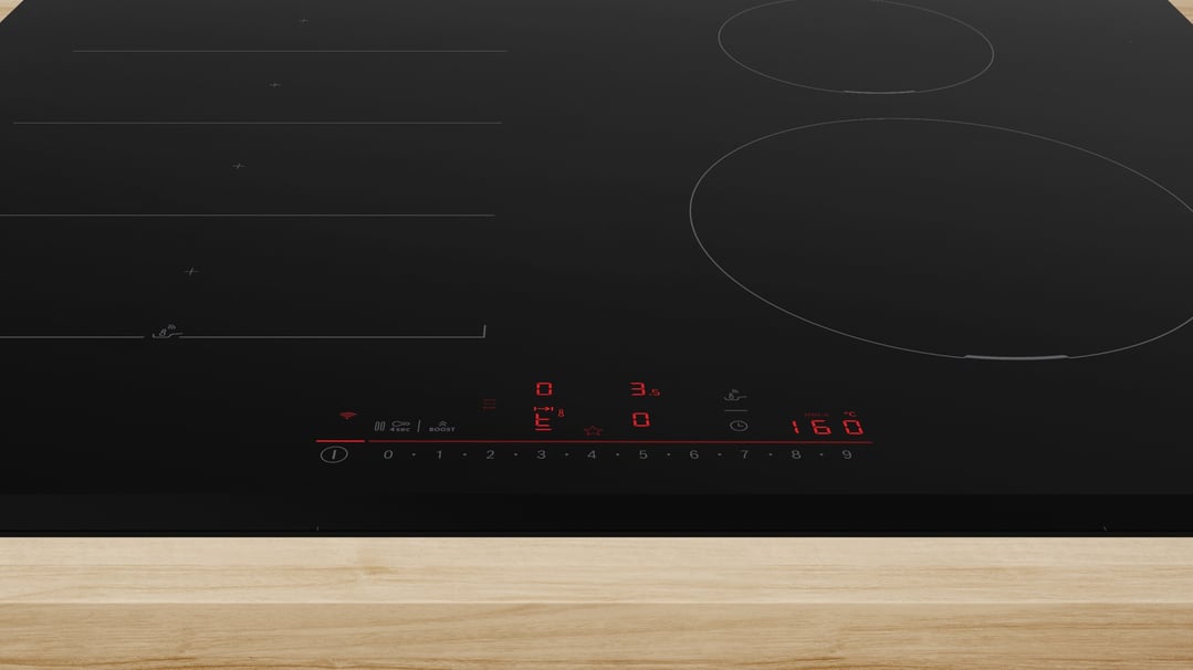 Close up of a black induction cooktop with red digital display on a wooden bench