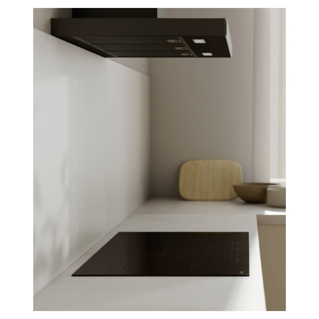 A black induction cooktop and rangehood in a modern kitchen with light walls