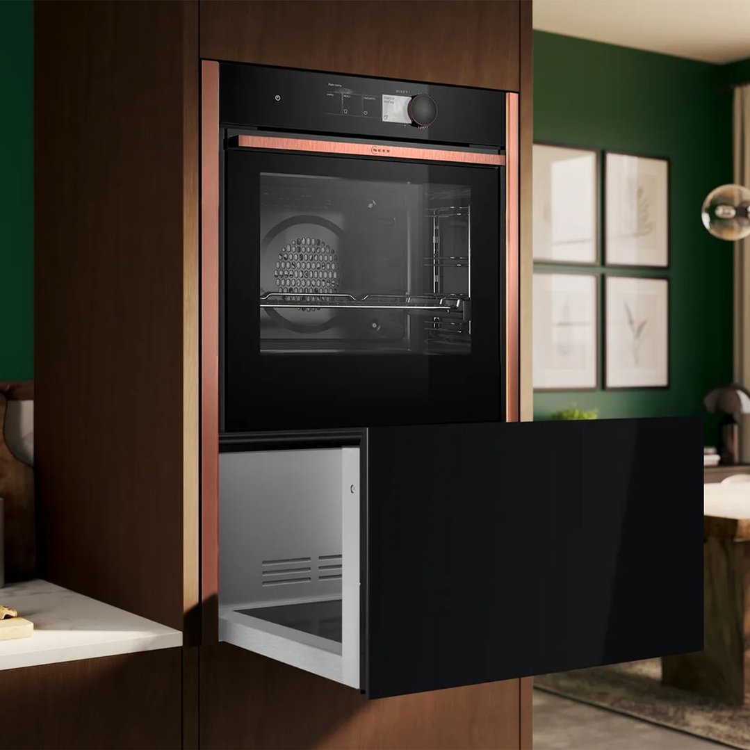 Built-in oven and warming drawer in a dark wood kitchen with green walls