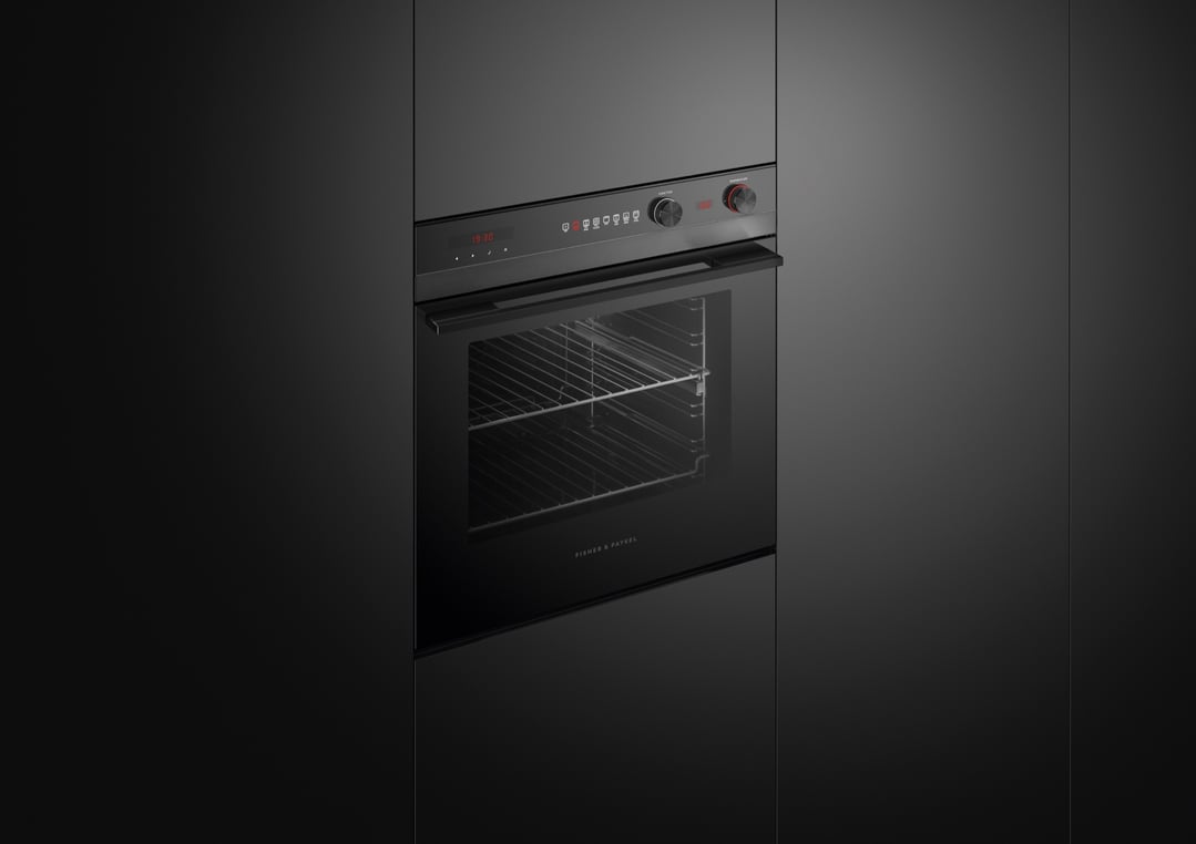 Black built-in oven with digital display and control knobs in a dark kitchen