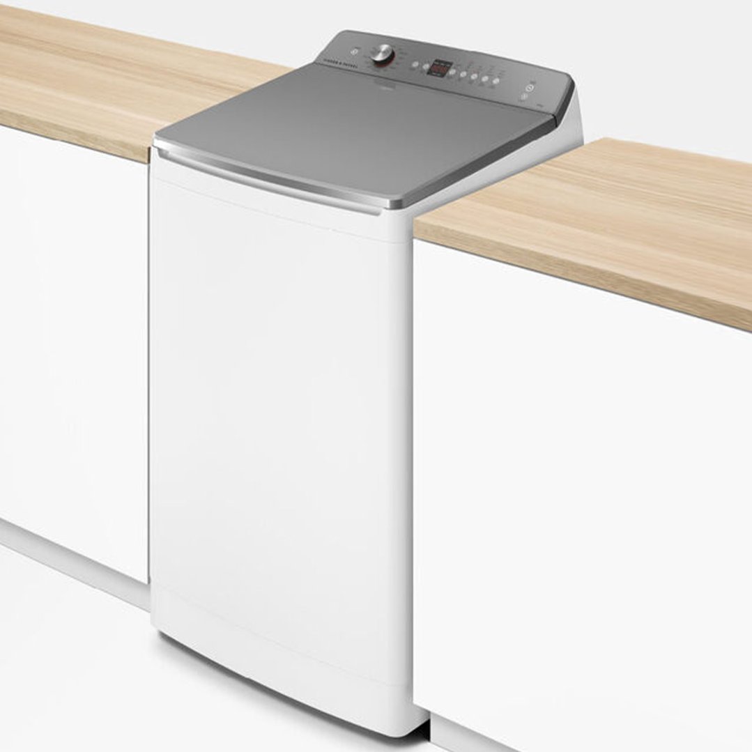 White top loader washing machine integrated into a wooden countertop