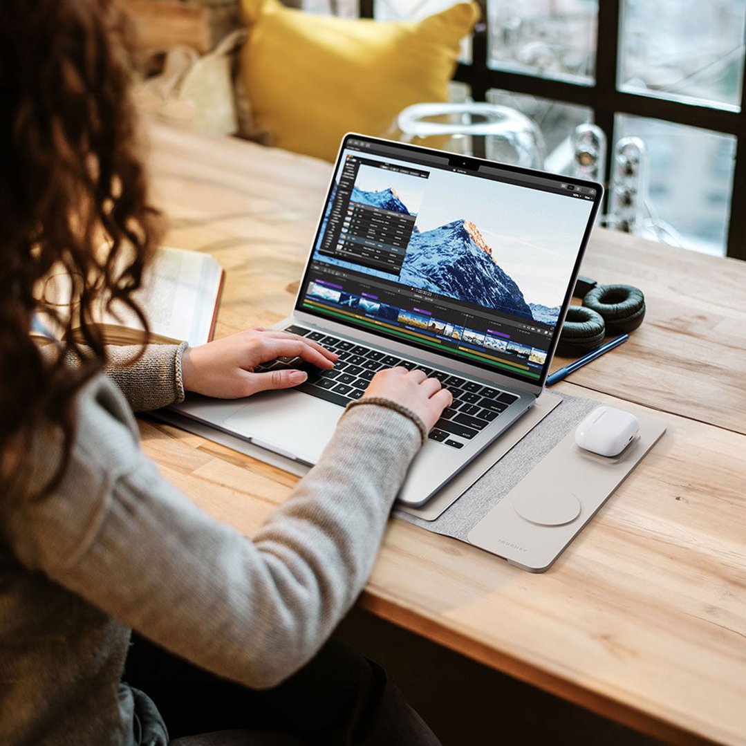 Woman using a laptop sleeve with wireless charging on a wooden table