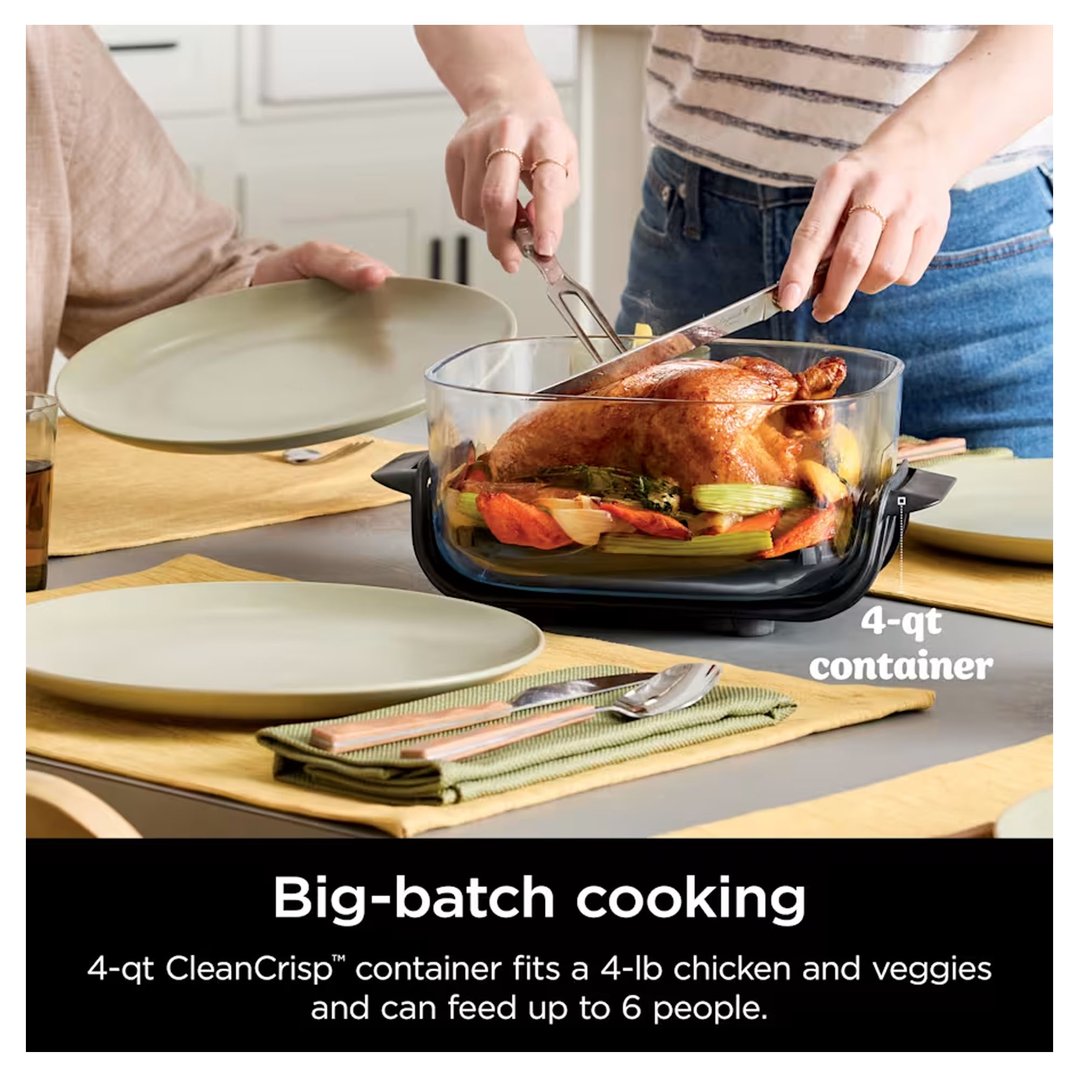 Two people serving a whole roasted chicken and vegetables from a glass air fryer