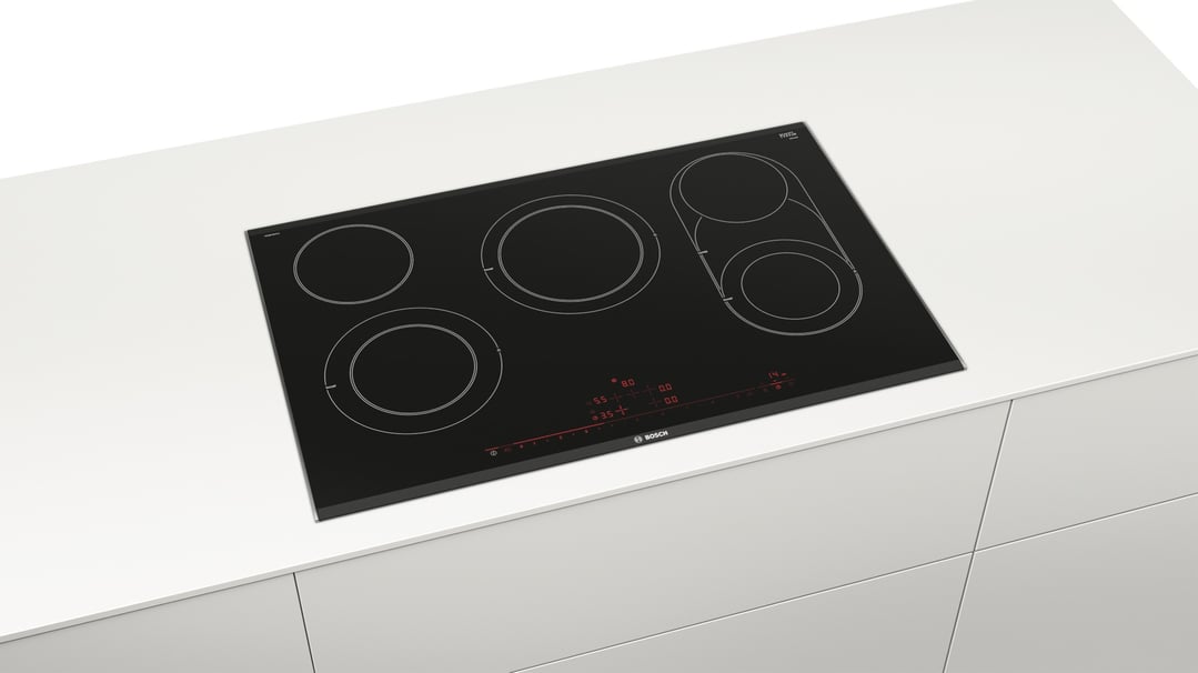 Black ceramic cooktop with five cooking zones built into a white countertop