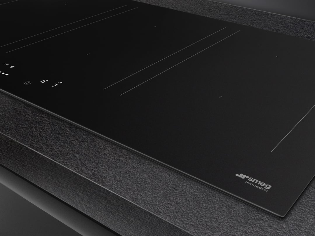 Close up of a black induction cooktop with controls on a dark countertop