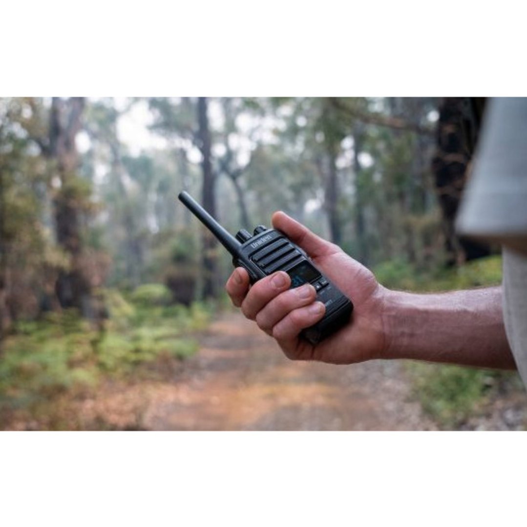 Hand holding a black UHF CB handheld radio in a forest