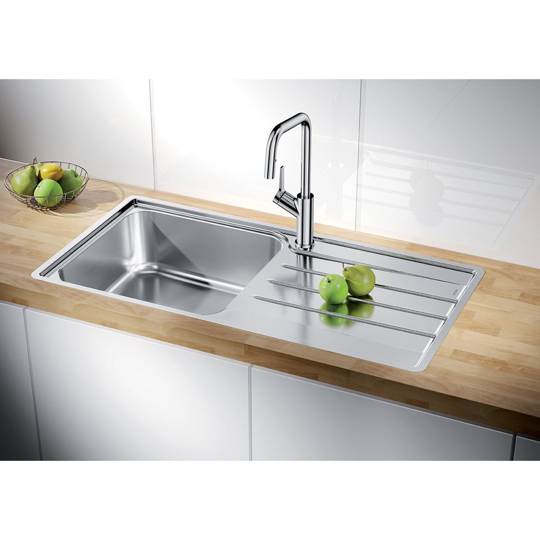 Stainless steel single bowl sink with drainer in a modern kitchen setting