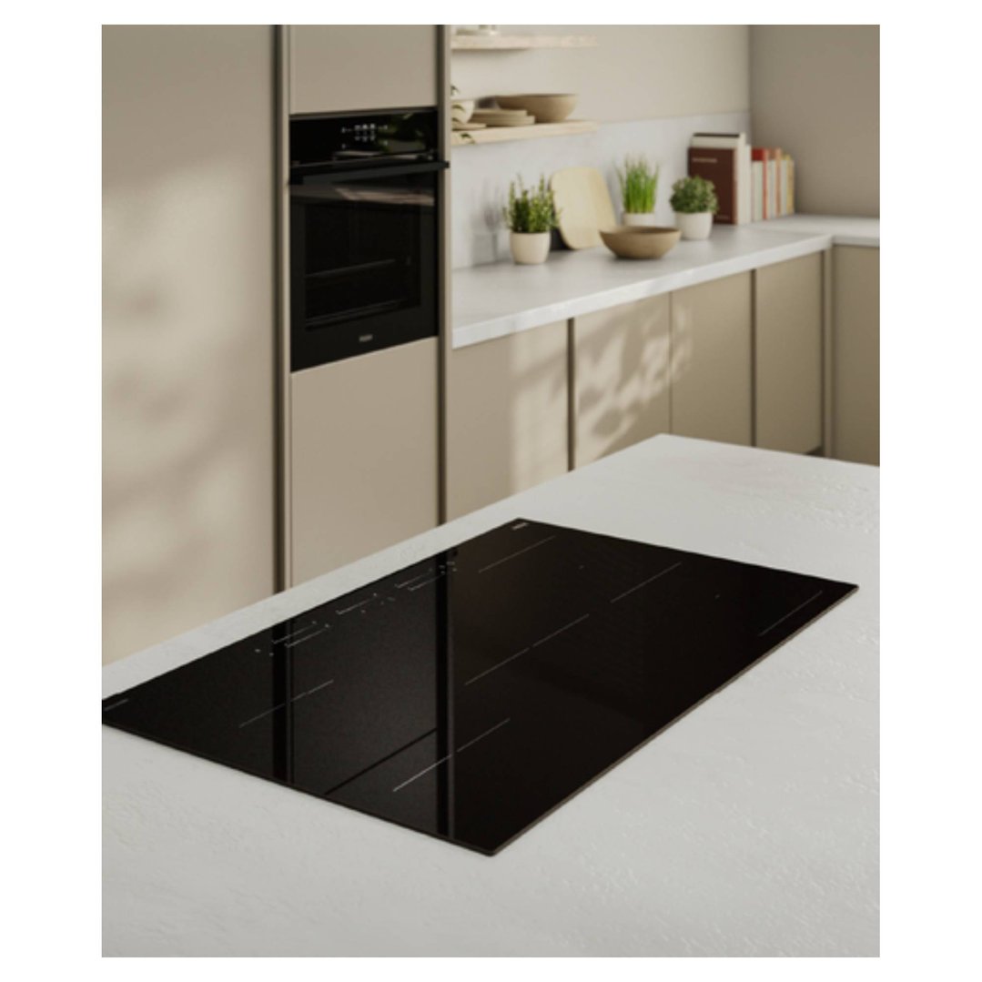 Black induction cooktop built into a white countertop in a modern kitchen