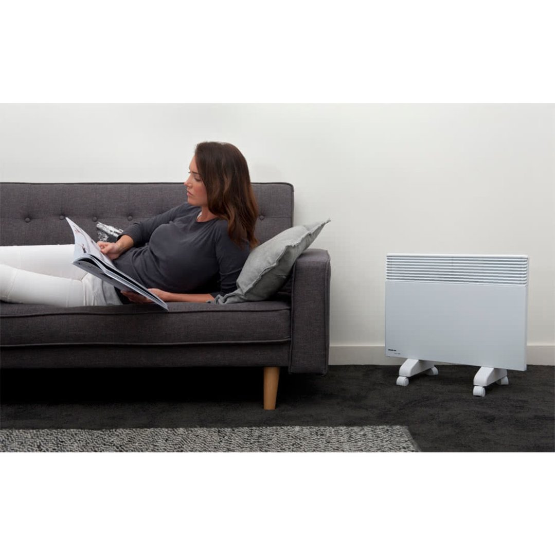Woman reading on a sofa with a white heater on the floor beside her