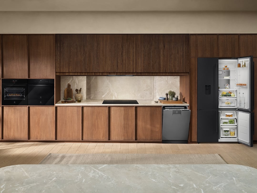 Black ovens, cooktop, dishwasher, and refrigerator in a modern kitchen setting