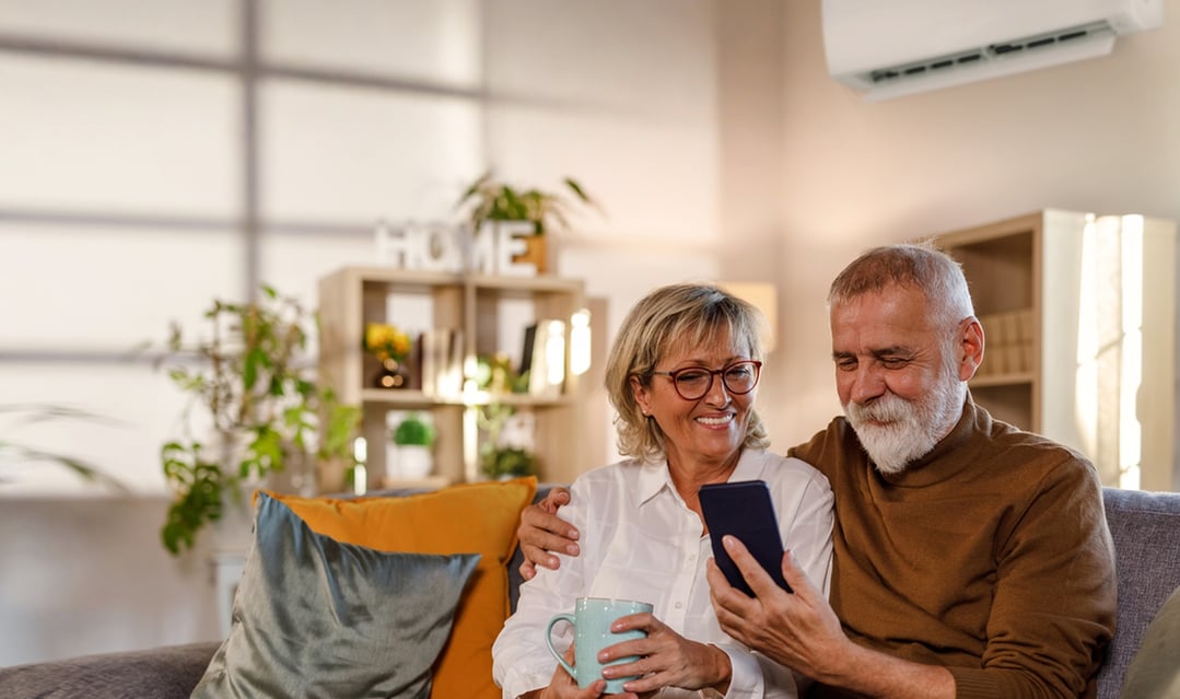 Elderly couple sitting on a sofa, looking at a smartphone