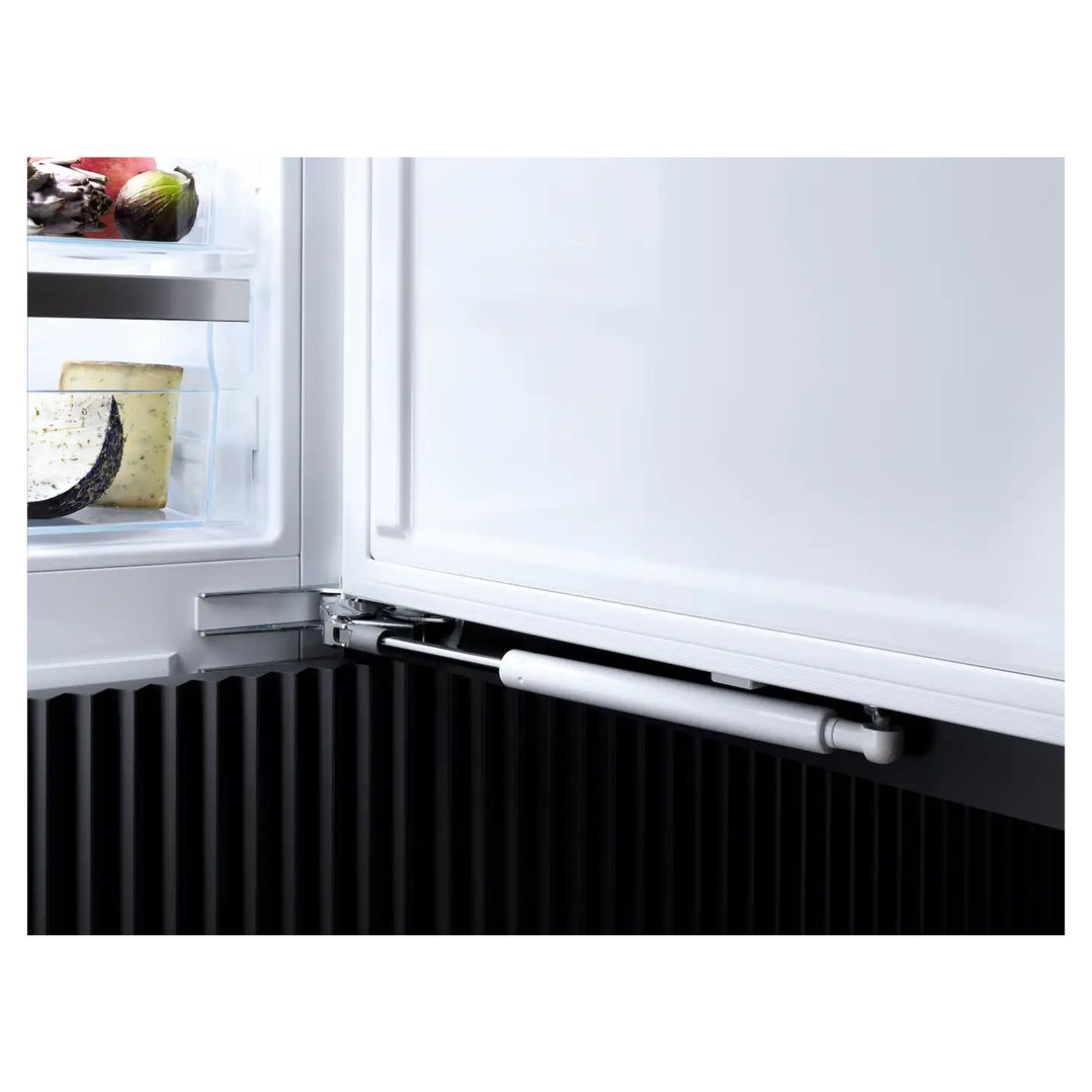 Open integrated fridge showing interior shelves with food and door hinge mechanism