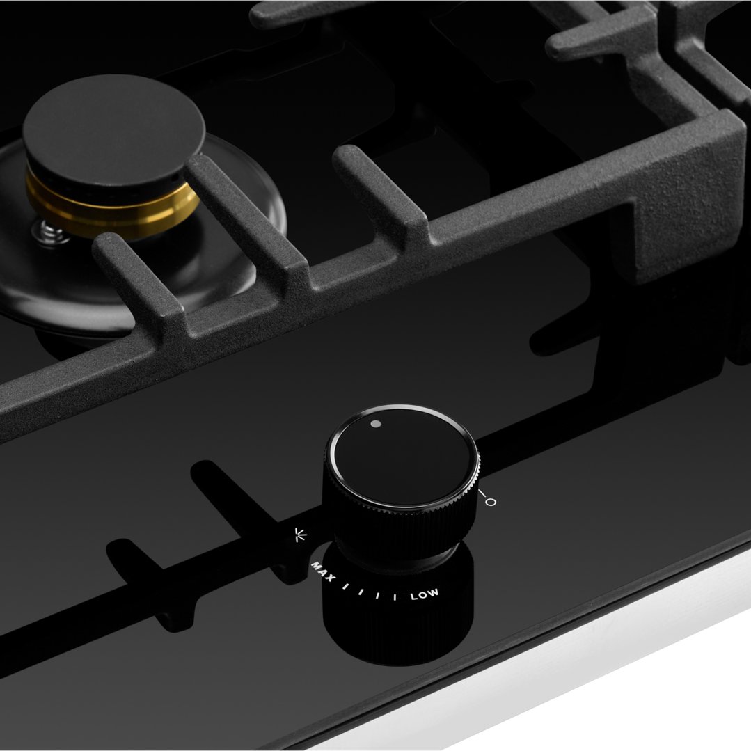 Close up of a black gas on glass cooktop with a control knob