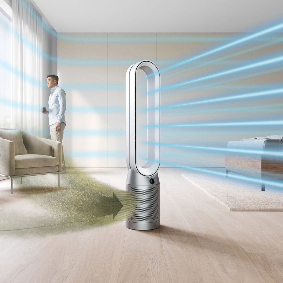 Man with a mug looking out a window, Dyson air purifier in a room