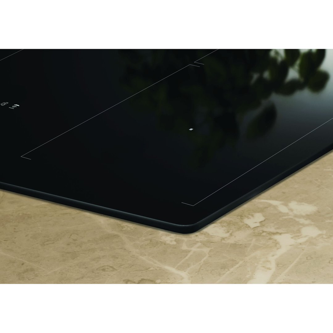 Close up of a black induction cooktop on a light brown marble countertop