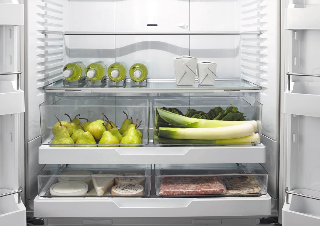 Open integrated refrigerator freezer with food items on shelves and in drawers