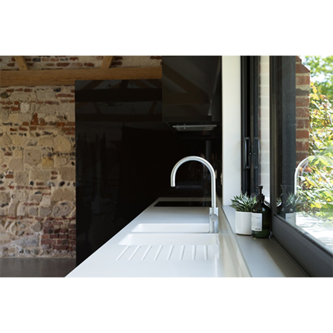 Brushed nickel tap on a white sink in a modern kitchen with brick walls