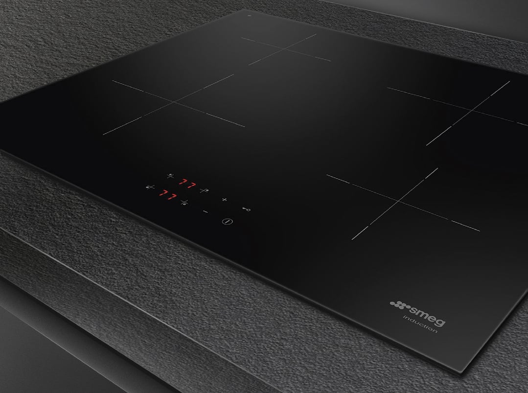 Black induction cooktop with illuminated controls on a dark textured countertop