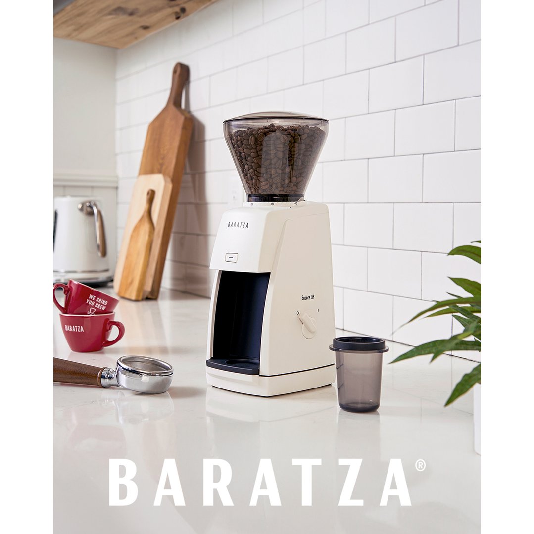 White coffee grinder on a kitchen counter with coffee beans and accessories