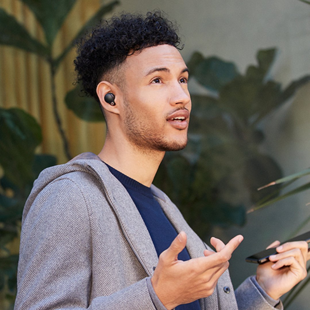 Man wearing black Wireless Noise Cancelling Headphones and holding a phone