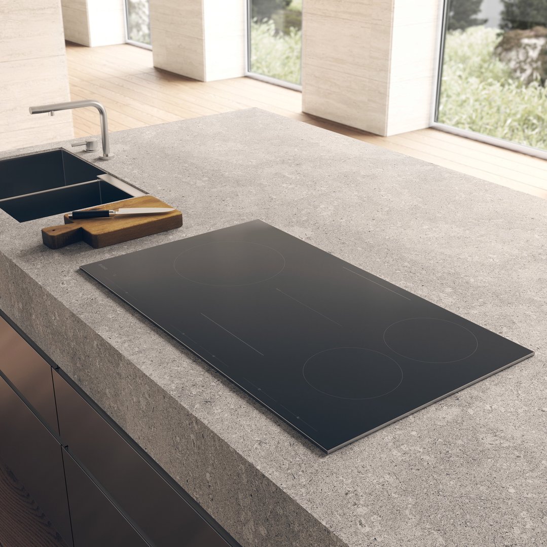 An ASKO induction hob cooktop built into a kitchen island with a sink
