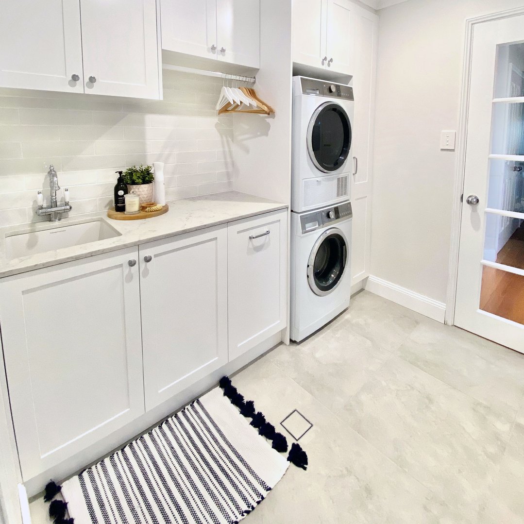 White laundry room with a sink, washer, dryer, and striped rug