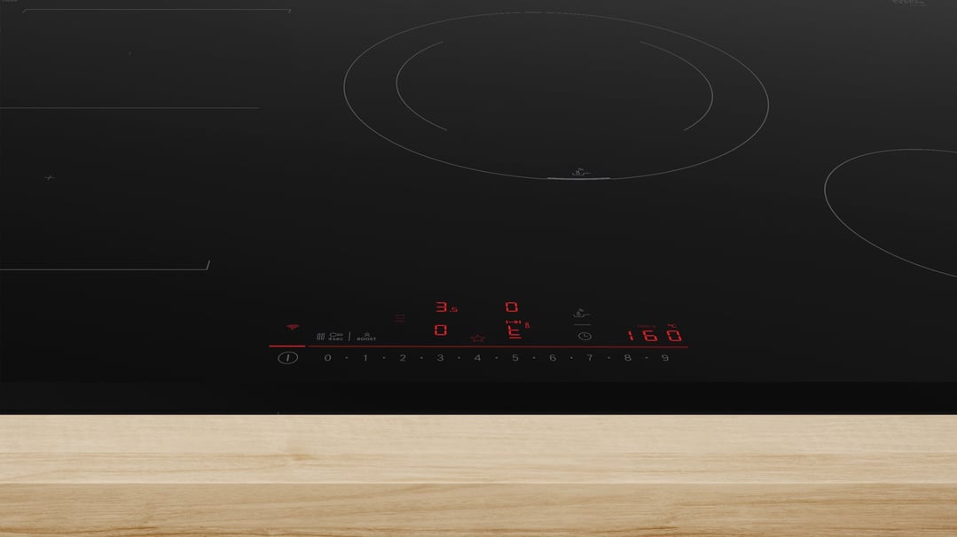 Black induction cooktop with illuminated controls, partially on a light wooden countertop