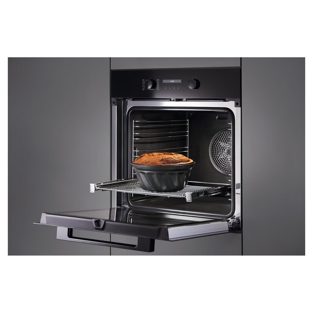 Built-in oven with a cake baking inside, door slightly ajar