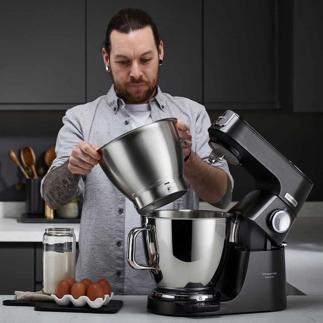 Man adding ingredients to a KENWOOD food mixer in a modern kitchen