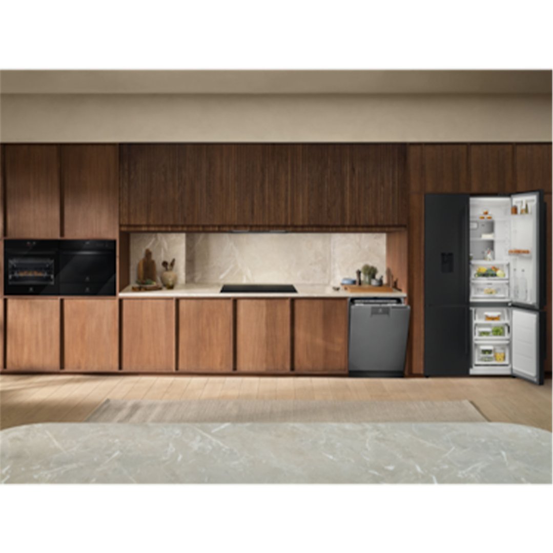 Black built-in ovens, cooktop, dishwasher, and open fridge in a modern kitchen