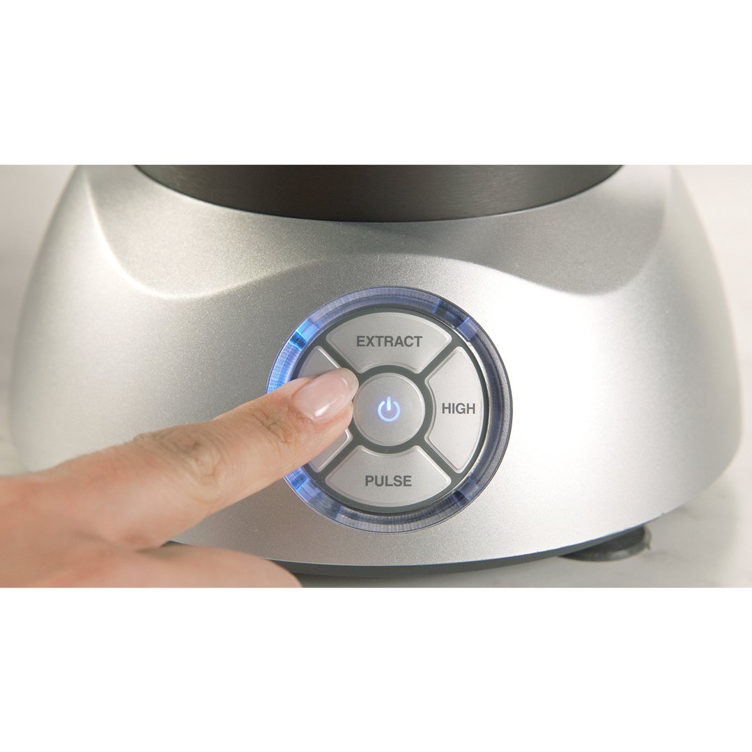 A finger pressing the power button on a silver NUTRiBULLET blender