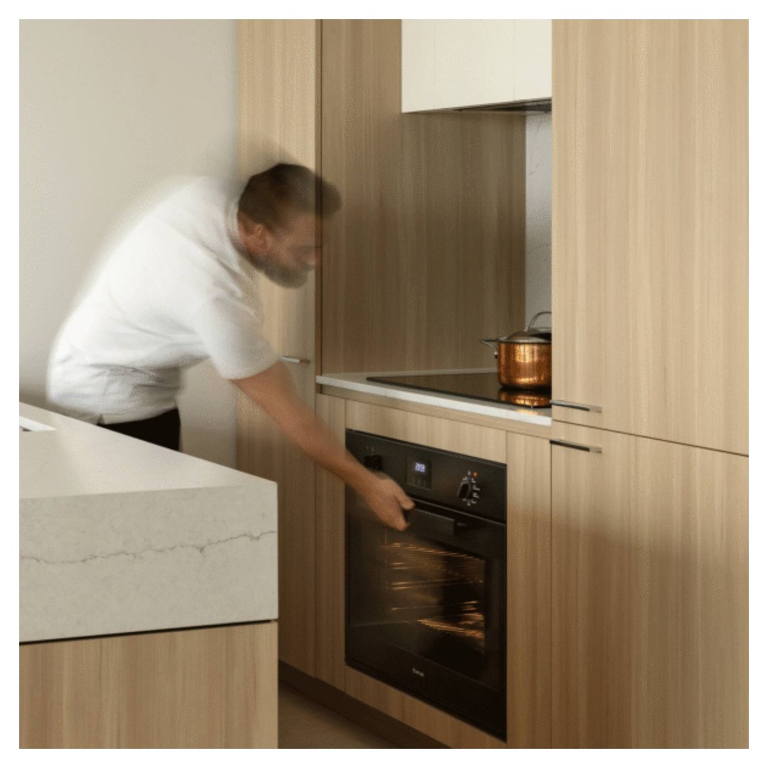 Man opening the built-in oven in a modern kitchen with wooden cabinets