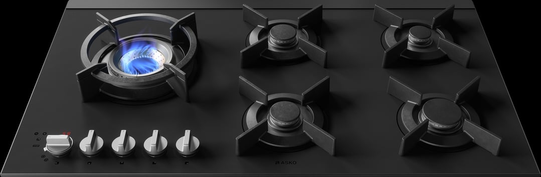Close-up of a black gas cooktop with one burner lit with blue flame