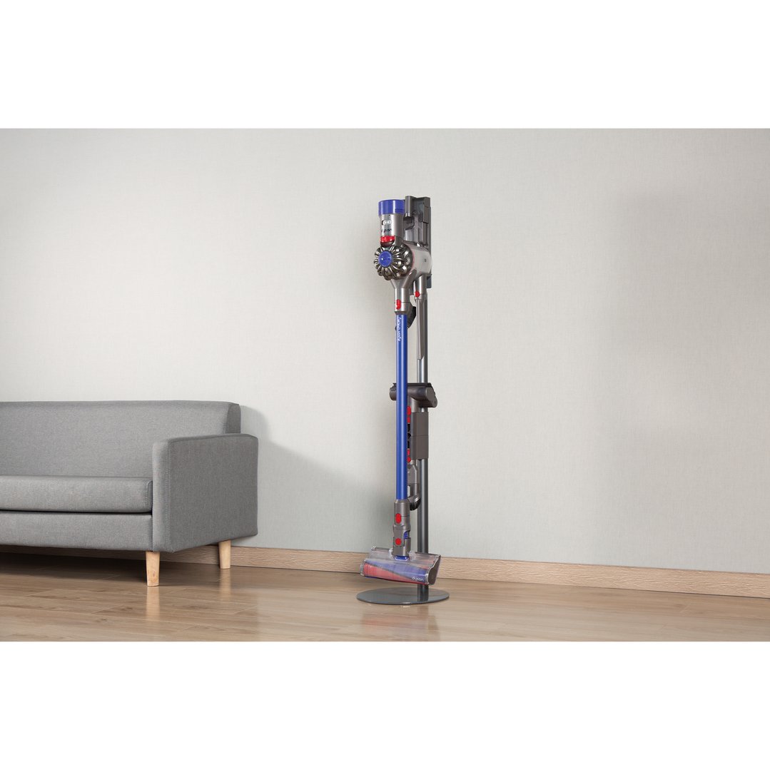 Dyson cordless vacuum on a floor stand next to a grey sofa
