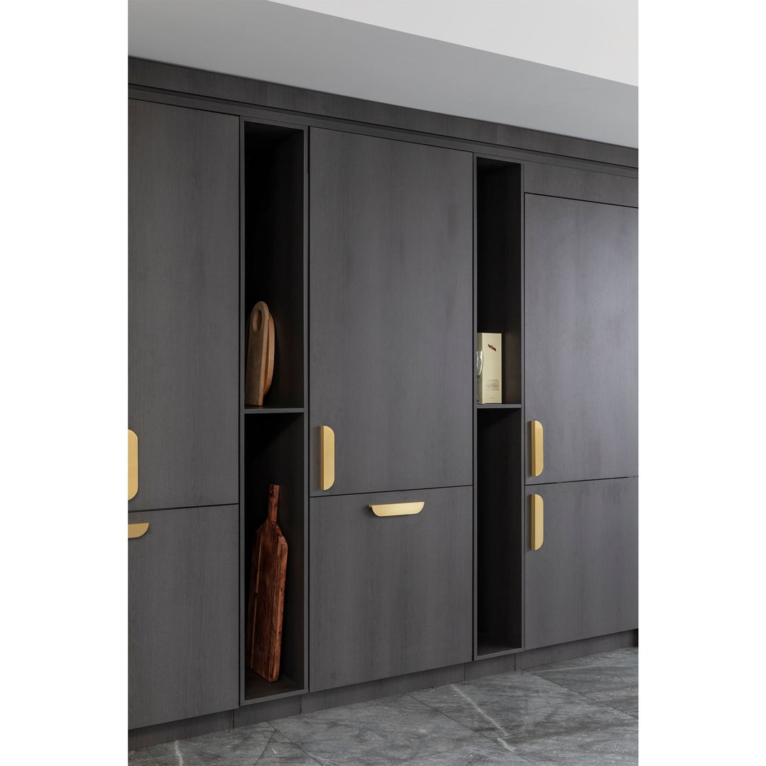 Integrated bottom mount fridge with dark wood panels and gold handles in a kitchen