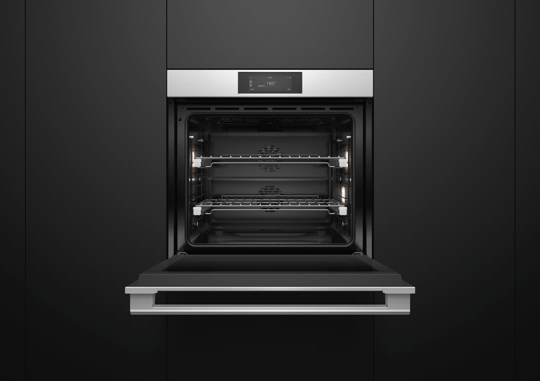 A stainless steel oven with its door open, built into a dark kitchen