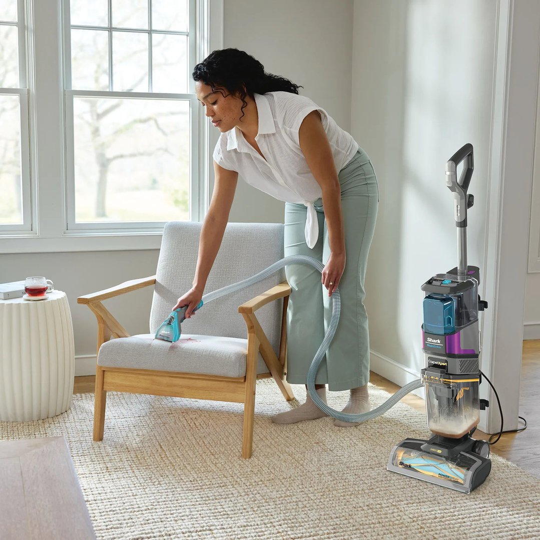 Woman cleaning a red stain from a chair with a Shark StainStriker vacuum cleaner