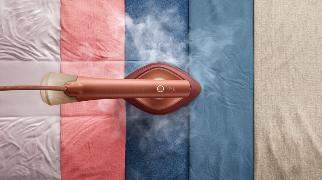 Philips OneTurn Hybrid Iron & Steamer steaming clothes on a flat surface