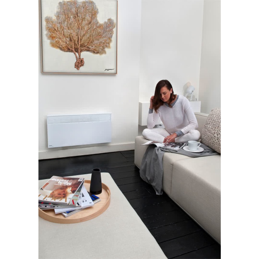 Woman reading on a sofa with a wall-mounted heater in a living room