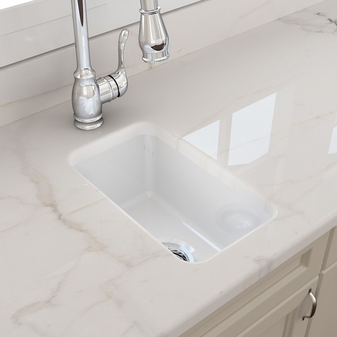 White fireclay sink with a chrome faucet in a kitchen setting