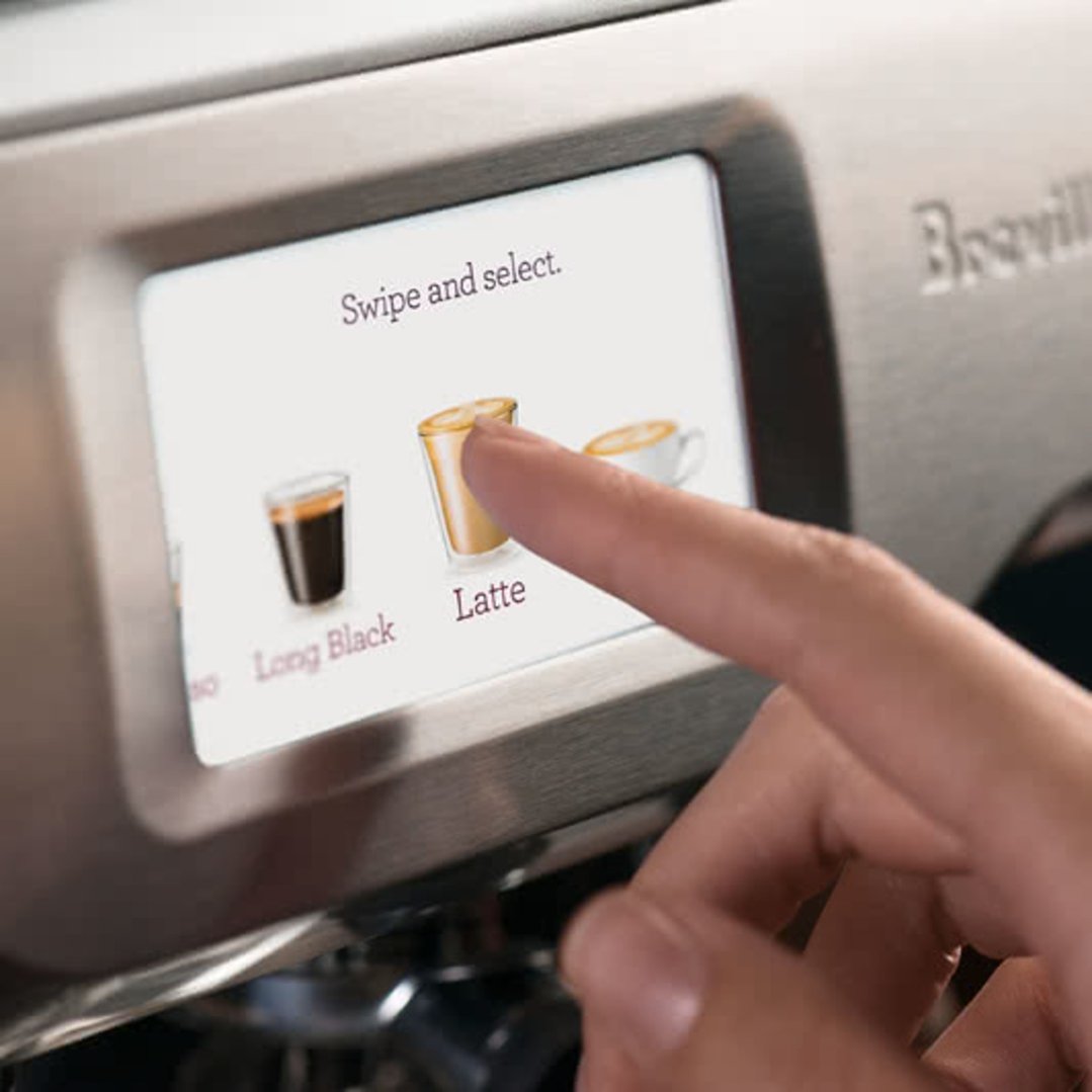 Hand selecting "Latte" on the touchscreen display of the Breville coffee machine
