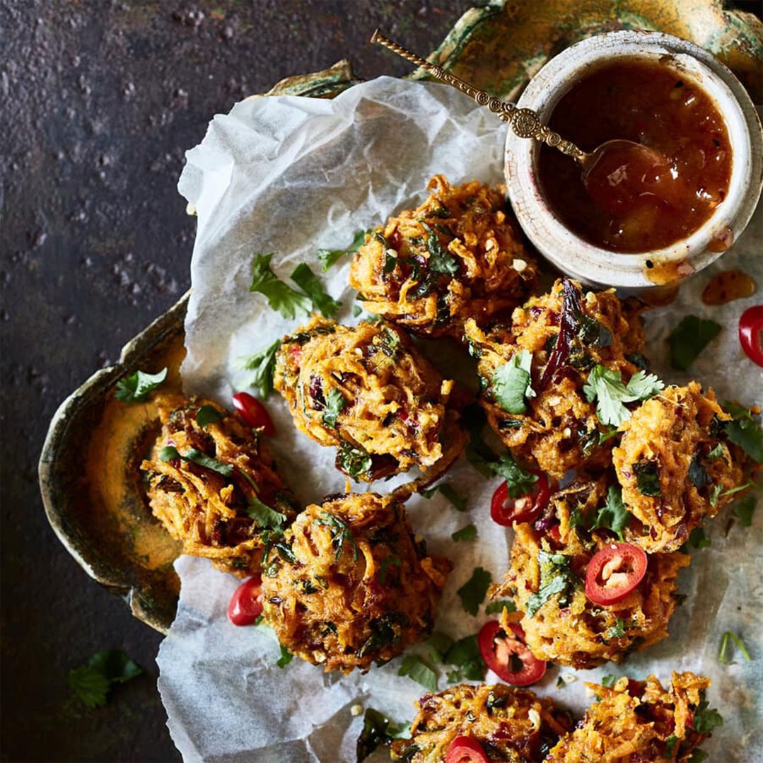 Close up of fried pakoras with sauce and chili on a tray