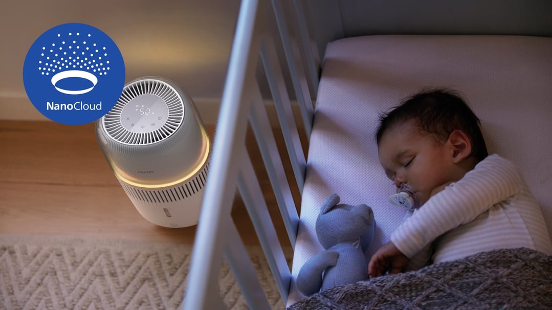 Philips Series 5000 evaporative humidifier next to a baby sleeping in a crib