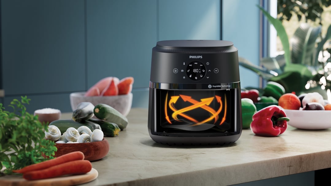 Black Philips airfryer on a kitchen counter with fresh vegetables