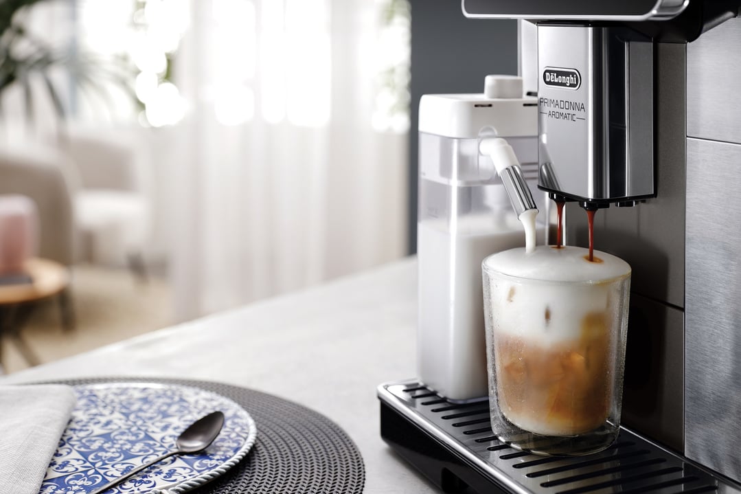 De'Longhi coffee machine making a layered iced coffee in a home setting