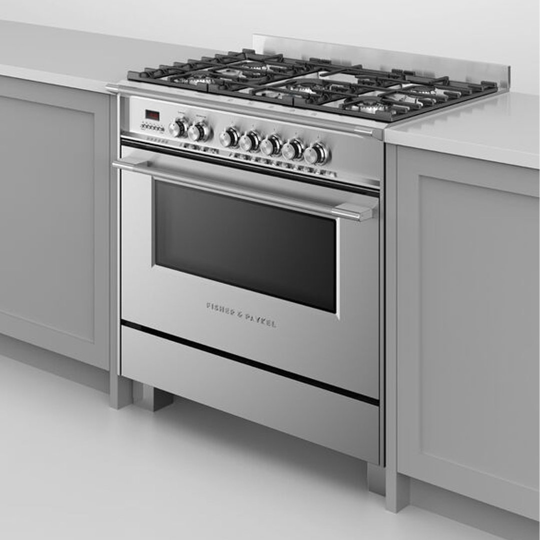 Stainless steel dual fuel cooker built into a light grey kitchen cabinet setting