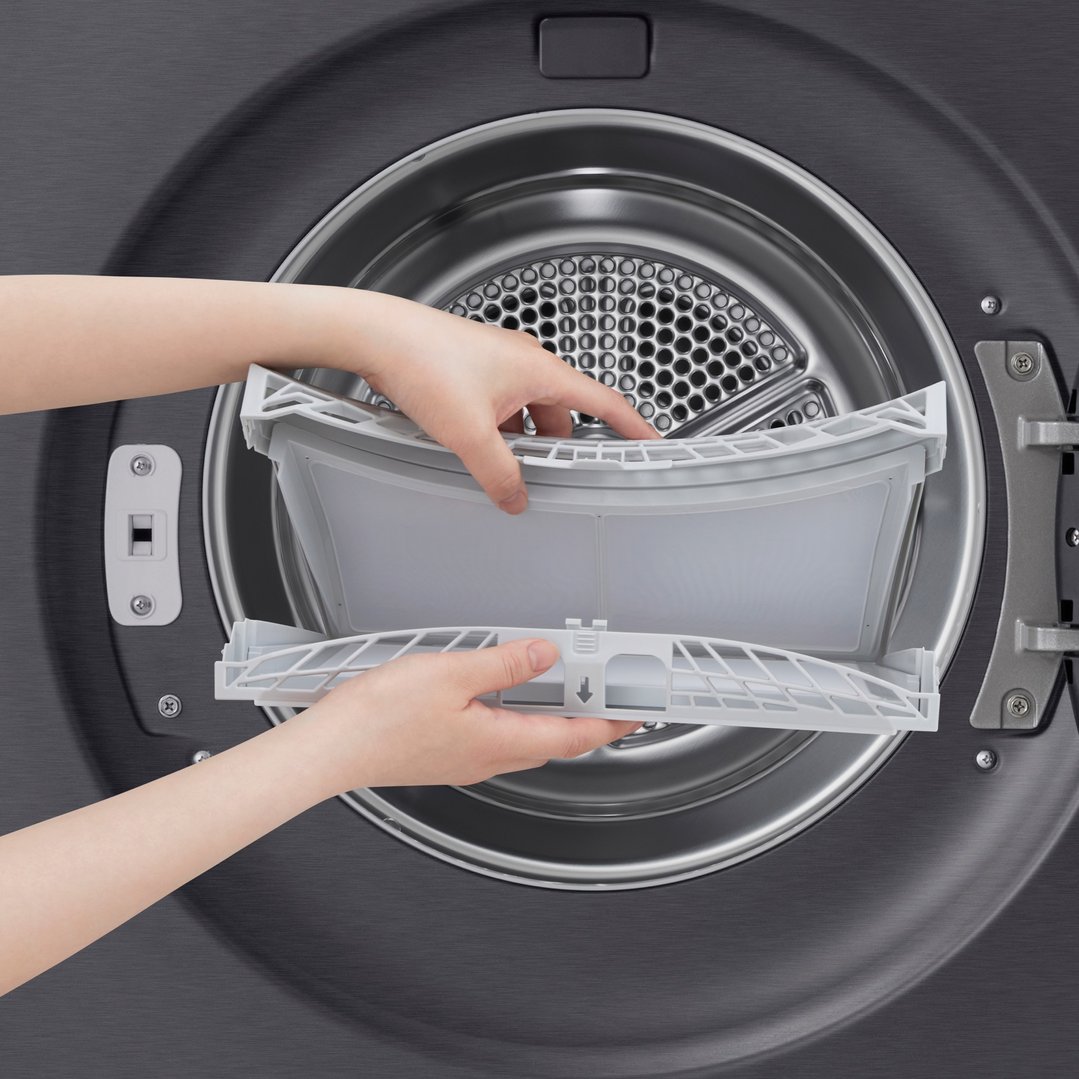 Hands removing the lint filter from the drum of a matte black dryer